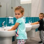 Dziewczynka i chłopiec myja ręce w umywalkach