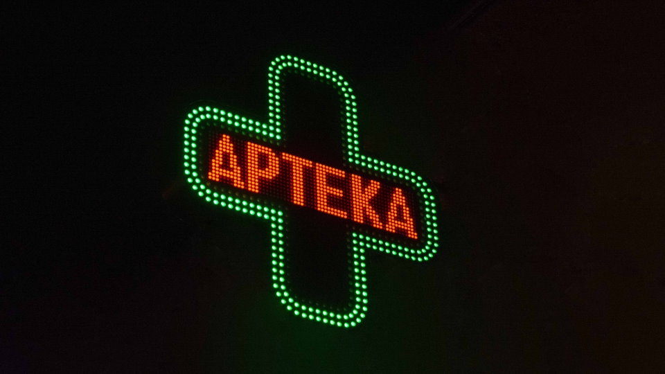 Świecący neon w kształcie zielonego krzyża i czerwonego napisu apteka